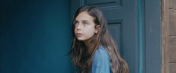 Movie still from “Mustang” (2015), directed by Deniz Gamze Ergüven – A girl with long hair is standing in front of a blue door; Close Up shot, Low angle