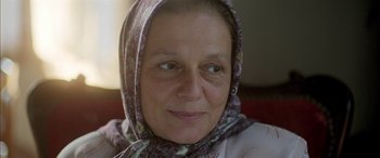 Movie still from “Mustang” (2015), directed by Deniz Gamze Ergüven – An older woman wearing a head scarf and smiling for the camera; Close Up shot, Over the shoulder angle