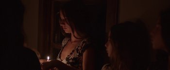 Movie still from “Mustang” (2015), directed by Deniz Gamze Ergüven – A woman standing next to another woman holding a candle in a dark room; Medium shot, Over the shoulder angle