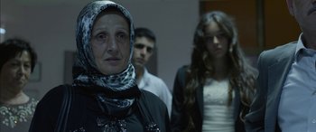 Movie still from “Mustang” (2015), directed by Deniz Gamze Ergüven – A woman wearing a headscarf standing in front of two other people; Close Up shot, Over the shoulder angle
