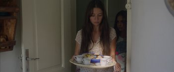 Movie still from “Mustang” (2015), directed by Deniz Gamze Ergüven – A woman holding a tray of food in front of a mirror; Medium shot, Over the shoulder angle