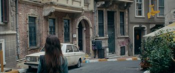 Movie still from “Mustang” (2015), directed by Deniz Gamze Ergüven – A car parked on the side of the road near a building; Wide shot, Over the shoulder angle
