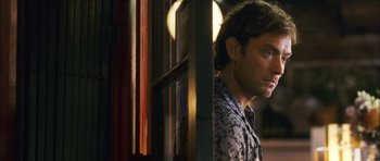 Movie still from “My Blueberry Nights” (2007), directed by Kar-Wai Wong – A man standing next to a window in a room; Close Up shot, Over the shoulder angle