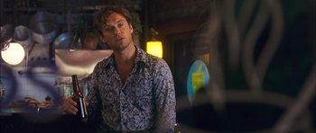 Movie still from “My Blueberry Nights” (2007), directed by Kar-Wai Wong – A man in a floral shirt looking at something in a mirror; Medium shot, Over the shoulder angle