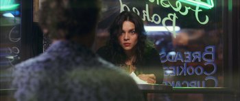 Movie still from “My Blueberry Nights” (2007), directed by Kar-Wai Wong – A woman sitting at a table in front of an umbrella; Close Up shot, Over the shoulder angle