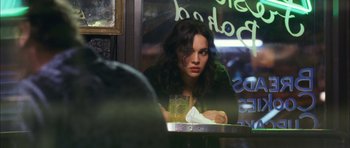 Movie still from “My Blueberry Nights” (2007), directed by Kar-Wai Wong – A woman sitting at a table with a glass of orange juice in front of her; Close Up shot, Over the shoulder angle