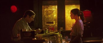 Movie still from “My Blueberry Nights” (2007), directed by Kar-Wai Wong – Two women are sitting at a bar and one of them is drinking; Medium shot, Over the shoulder angle