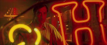 Movie still from “My Blueberry Nights” (2007), directed by Kar-Wai Wong – A man in a yellow shirt is in front of a neon sign; Close Up shot, Low angle