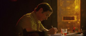 Movie still from “My Blueberry Nights” (2007), directed by Kar-Wai Wong – A man writing on a piece of paper at a table; Medium shot, High angle
