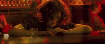 Movie still from “My Blueberry Nights” (2007), directed by Kar-Wai Wong – A woman sitting at a table with a glass of water; Close Up shot, High angle