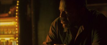 Movie still from “My Blueberry Nights” (2007), directed by Kar-Wai Wong – An older man sitting in the dark with a cup; Close Up shot, Over the shoulder angle