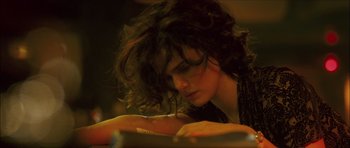 Movie still from “My Blueberry Nights” (2007), directed by Kar-Wai Wong – A person sitting at a table reading a book; Close Up shot, High angle