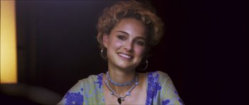 Movie still from “My Blueberry Nights” (2007), directed by Kar-Wai Wong – A woman with curly blonde hair wearing a necklace and earrings; Close Up shot, Over the shoulder angle