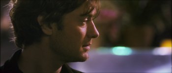 Movie still from “My Blueberry Nights” (2007), directed by Kar-Wai Wong – A young man's face in the dark; Close Up shot, Over the shoulder angle