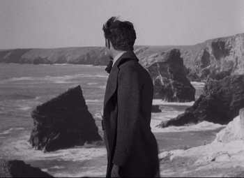 Movie still from “My Cousin Rachel” (1952), directed by Henry Koster – A man standing on the beach looking out at the ocean; Wide shot, High angle