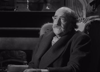 Movie still from “My Cousin Rachel” (1952), directed by Henry Koster – An older man sitting in a chair with his hand on his shoulder; Close Up shot, High angle