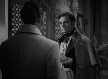 Movie still from “My Cousin Rachel” (1952), directed by Henry Koster – A man in a trench coat is talking to another man in a trench coat; Medium shot, Over the shoulder angle