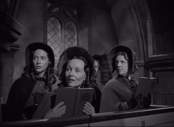 Movie still from “My Cousin Rachel” (1952), directed by Henry Koster – A group of women in hats holding books in front of a window; Medium shot, Low angle