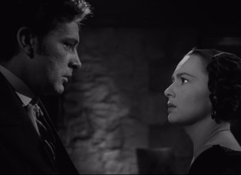 Movie still from “My Cousin Rachel” (1952), directed by Henry Koster – A man and a woman face to face in front of a stone wall; Close Up shot, Low angle