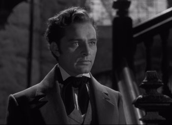 Movie still from “My Cousin Rachel” (1952), directed by Henry Koster – A man wearing a suit and tie standing in front of a building; Close Up shot, Low angle