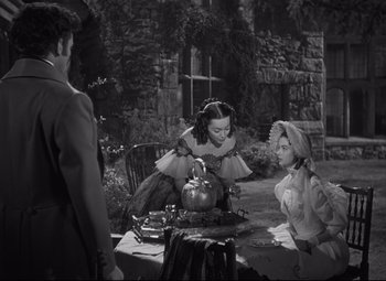 Movie still from “My Cousin Rachel” (1952), directed by Henry Koster – Two women and a man are sitting at a table with a pumpkin on top of it; Medium shot, High angle