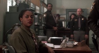 Movie still from “My Cousin Vinny” (1992), directed by Jonathan Lynn – A woman sitting at a desk in front of two men; Medium shot, Over the shoulder angle