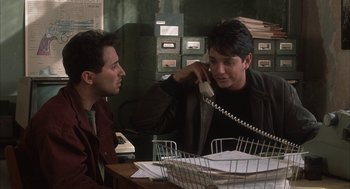 Movie still from “My Cousin Vinny” (1992), directed by Jonathan Lynn – Two men sitting at a table talking on the phone; Medium shot, Over the shoulder angle