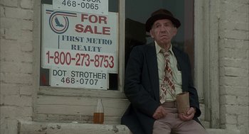 Movie still from “My Cousin Vinny” (1992), directed by Jonathan Lynn – An older man sitting in front of a for sale sign; Medium shot, Low angle