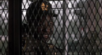 Movie still from “My Cousin Vinny” (1992), directed by Jonathan Lynn – A man in a uniform is behind a chain link fence; Close Up shot, Over the shoulder angle