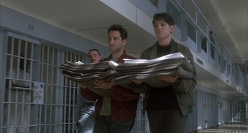 Movie still from “My Cousin Vinny” (1992), directed by Jonathan Lynn – A group of men standing next to each other holding newspapers; Medium shot, Low angle