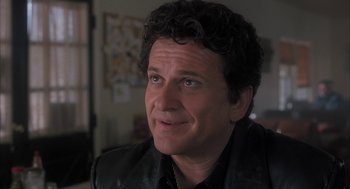 Movie still from “My Cousin Vinny” (1992), directed by Jonathan Lynn – A person with curly hair wearing a black jacket; Close Up shot, Over the shoulder angle