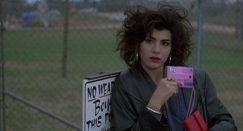 Movie still from “My Cousin Vinny” (1992), directed by Jonathan Lynn – A woman holding up a sign while standing next to a fence; Close Up shot, Low angle