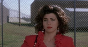 Movie still from “My Cousin Vinny” (1992), directed by Jonathan Lynn – A person wearing a red jacket near a fence; Close Up shot, Over the shoulder angle
