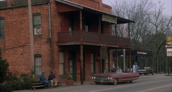 Movie still from “My Cousin Vinny” (1992), directed by Jonathan Lynn – Two men sit on a bench in front of a brick building; Wide shot, High angle
