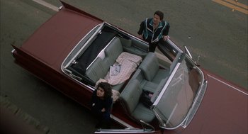 Movie still from “My Cousin Vinny” (1992), directed by Jonathan Lynn – Two people standing in the back seat of a convertible car; Wide shot, Overhead angle