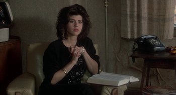 Movie still from “My Cousin Vinny” (1992), directed by Jonathan Lynn – A woman sitting in a chair with her hands clasped in front of a book; Medium shot, High angle