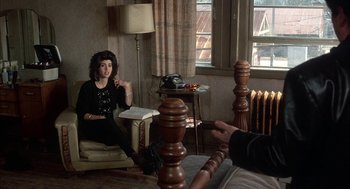 Movie still from “My Cousin Vinny” (1992), directed by Jonathan Lynn – A woman sitting on a chair in a living room; Medium shot, Over the shoulder angle