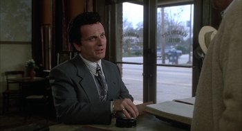 Movie still from “My Cousin Vinny” (1992), directed by Jonathan Lynn – A man sitting at a table in front of an open window; Medium shot, Low angle