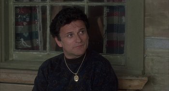 Movie still from “My Cousin Vinny” (1992), directed by Jonathan Lynn – A man sitting in front of a window wearing a necklace; Close Up shot, Over the shoulder angle