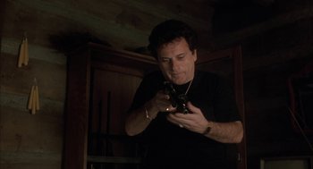 Movie still from “My Cousin Vinny” (1992), directed by Jonathan Lynn – A man looking at his cell phone while standing in a room; Medium shot, Low angle