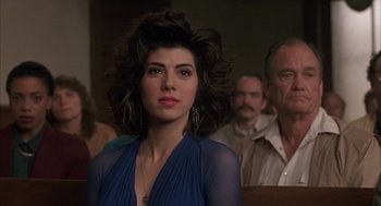 Movie still from “My Cousin Vinny” (1992), directed by Jonathan Lynn – A woman in a blue dress in front of a group of people; Close Up shot, Over the shoulder angle