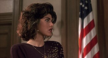 Movie still from “My Cousin Vinny” (1992), directed by Jonathan Lynn – A woman in a black dress and a gold necklace; Close Up shot, Over the shoulder angle