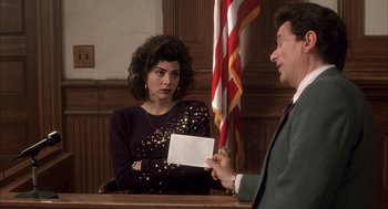 Movie still from “My Cousin Vinny” (1992), directed by Jonathan Lynn – A man and a woman in front of an american flag in a court room; Medium shot, Over the shoulder angle