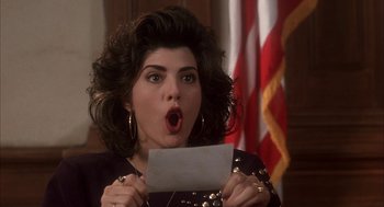 Movie still from “My Cousin Vinny” (1992), directed by Jonathan Lynn – A woman holding a piece of paper in front of her face; Close Up shot, High angle