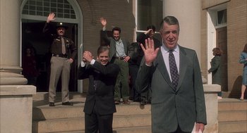 Movie still from “My Cousin Vinny” (1992), directed by Jonathan Lynn – A group of men standing on the front steps of a building; Medium shot, Over the shoulder angle