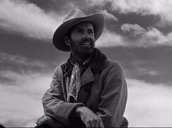 Movie still from “My Darling Clementine” (1946), directed by John Ford – A man wearing a cowboy hat sitting on top of a hill; Close Up shot, Low angle