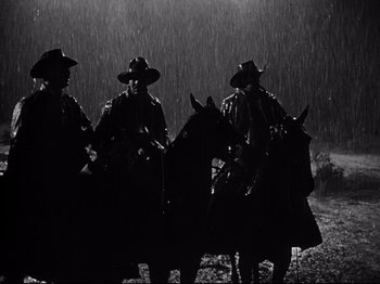Movie still from “My Darling Clementine” (1946), directed by John Ford – A group of men on horses in the rain; Wide shot, Low angle