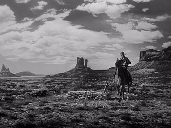 Movie still from “My Darling Clementine” (1946), directed by John Ford – A man riding a horse in a field with mountains in the background; Wide shot, Low angle