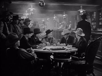 Movie still from “My Darling Clementine” (1946), directed by John Ford – A black and white photo of a group of men sitting around a table; Wide shot, High angle