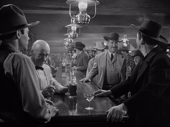 Movie still from “My Darling Clementine” (1946), directed by John Ford – A black and white photo of a group of men sitting at a bar; Medium shot, Low angle